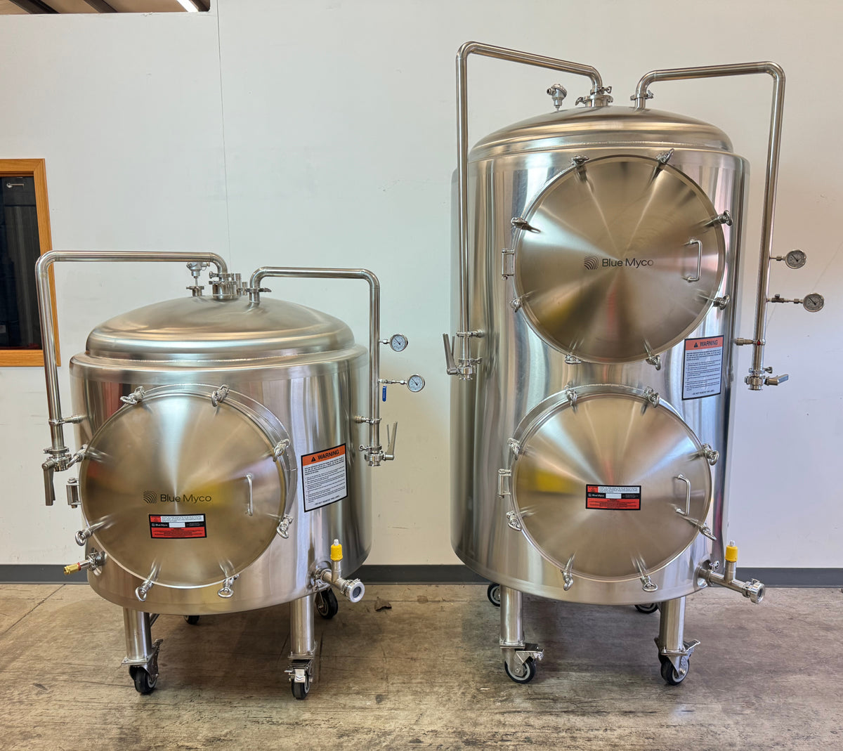 Two stainless steel Blue Myco Autoclaves on casters, one smaller and one larger, photographed indoors against a plain wall.